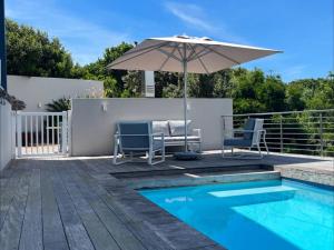 a patio with an umbrella and chairs and a pool at Dolphin Dream in Herolds Bay