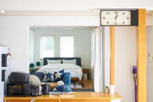 宮崎的住宿－Surf&Turf Aoshima - サーフ&ターフ青島 -，卧室配有一张床,墙上挂着一个钟
