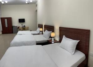 a hotel room with three beds and a television at Family rooms with beach view يستضيف مكان الإقامة هذا العائلات فقط in Ajman 