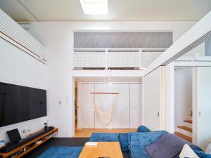 un salon avec un canapé bleu et une télévision dans l'établissement Surf&Turf Aoshima - サーフ&ターフ青島 -, à Miyazaki