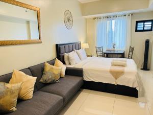 a bedroom with a bed and a couch at PREMIUM CONDO AT BRENTHILL BAGUIO in Baguio