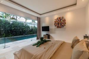 a bedroom with a bed and a large window at Villa Kallayaan by Optimum Bali Villas in Seminyak