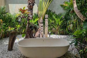 a bath tub in a garden with some statues at Villa Kallayaan by Optimum Bali Villas in Seminyak