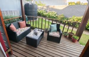 a porch with two chairs and a table and some plants at 139 Longships - Self Catering Flatlet in Plettenberg Bay