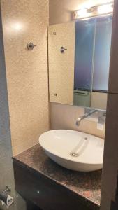 een badkamer met een witte wastafel en een spiegel bij hotel ryan in New Delhi