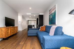 a living room with a blue couch and a flat screen tv at Contemporary Tri-Level APT in a Prime Central Spot in Canberra