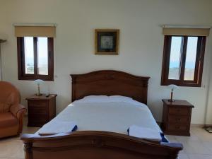 a bedroom with a bed and a chair and windows at Nayia Paradise Villa! Best Villa in Cyprus in Paphos
