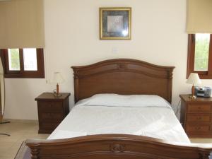 a bedroom with a large wooden bed and two night stands at Nayia Paradise Villa! Best Villa in Cyprus in Paphos City