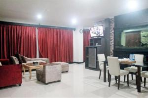 - un salon avec des rideaux rouges, une table et des chaises dans l'établissement Cikidang Resort, à Sukabumi