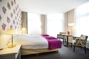 - une chambre avec un grand lit et une couverture violette dans l'établissement Hotel Wesseling, à Dwingeloo