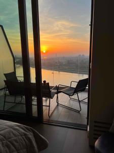 Cette chambre dispose d'un balcon avec deux chaises et un coucher de soleil. dans l'établissement BW TERRACE top floor apartments with river view & self check-in, à Belgrade