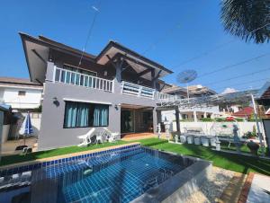 a villa with a swimming pool in front of a house at Deluxe Pool Villa close to Beach and Walking Street! in Pattaya