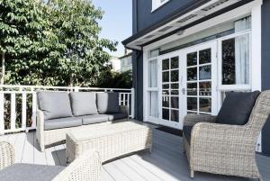 un patio con sillas de mimbre y un sofá en una terraza en Lovingly Restored Hampton's Haven, en Kings Park