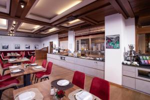 un restaurante con mesas de madera y sillas rojas en ALPIN- Das Sporthotel - SKI IN SKI OUT cityXpress, SUMMERCARD INCLUDED en Zell am See