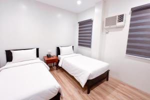 1 dormitorio con 2 camas y ventana en SANTOS Pension House en Manila