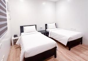 two beds in a room with white sheets at SANTOS Pension House in Manila