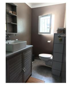 een badkamer met een wastafel, een toilet en een raam bij Chez Sonia in Sarrians
