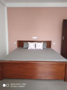 a bed with a wooden frame and two pillows on it at Coastal Cloud in Hikkaduwa