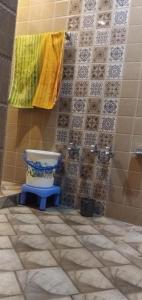 baño con aseo y pared de azulejos en WANI GUEST HOUSE, en Gulmarg