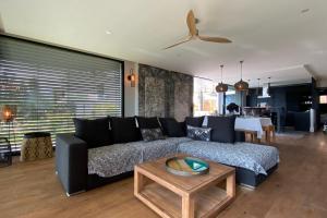 uma sala de estar com um sofá preto e uma mesa em Villa Juco - 4 Bedroom Villa Pool Sauna - Lake View em Sévrier