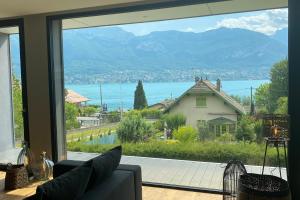 uma sala de estar com uma grande janela com vista para uma casa em Villa Juco - 4 Bedroom Villa Pool Sauna - Lake View em Sévrier