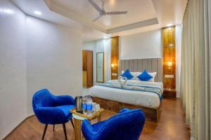 a bedroom with a bed and two blue chairs at Astra Luxury Rooms and Cafe in Varanasi