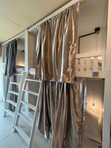 a bunk bed with a curtain in a room at Lay Low AC Hostel Nr Airport Ubon ที่พัก เลโล in Ubon Ratchathani