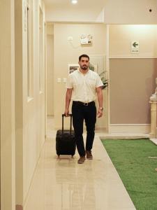 Um homem a andar pelo corredor com uma mala. em Mak Suites em Piura