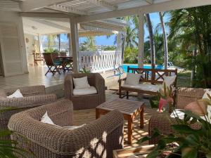 un patio con sillas y mesas en un porche en Villa Baleine Bleue piscine&vue, en Saint-Paul