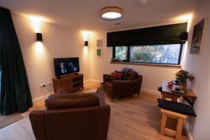 uma sala de estar com duas cadeiras e uma televisão em Forest Corner Luxury Apartment with Hot Tub em North Ballachulish