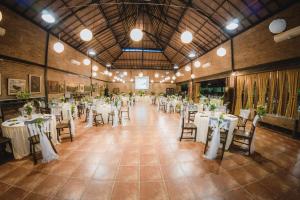 um salão de banquetes com mesas e cadeiras brancas em Hills Joglo Villa em Ungaran