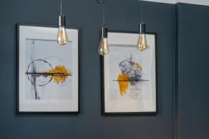drie ingelijste foto's aan een muur met lichten bij Elegant Apartment near to the Centre of Poznań by Rent like home in Poznań