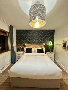 una camera da letto con un grande letto bianco e un lampadario a braccio di Blush Jungle a Dublino