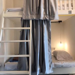 a bunk bed with a curtain in a room at Lay low hostel in Ubon Ratchathani