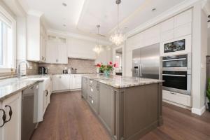 a large kitchen with white cabinets and a large island at Dunbar Luxury Homestay in Vancouver