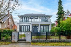 una casa blanca con una valla negra en Dunbar Luxury Homestay, en Vancouver