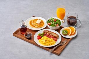 a tray with plates of breakfast food and orange juice at Imperial Palace Boutique Hotel Itaewon - Renovated in 2025 in Seoul