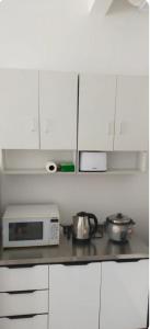 a kitchen with white cabinets and a microwave at Camelia Youth City Nilai Studio residence 5pax in Nilai