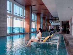 una mujer sentada en el agua en una piscina en Renaissance Bangkok Ratchaprasong Hotel en Bangkok