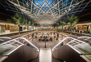 a large shopping mall with a large ceiling and palm trees at Dusit Thani Abu Dhabi in Abu Dhabi