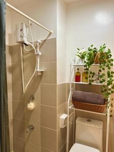 a bathroom with a shower and a toilet with plants at The Cubbies in Manila