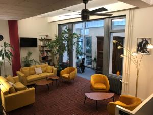 - un salon avec des canapés et des chaises jaunes dans l'établissement Logis Hôtel du Midi - Saint Etienne Sud, à Saint-Étienne