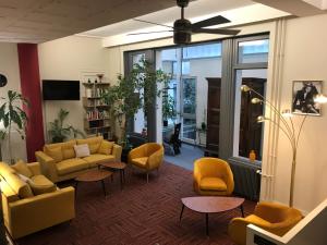 una sala de estar con sillones y sillas de color amarillo en Logis Hôtel du Midi - Saint Etienne Sud, en Saint-Étienne