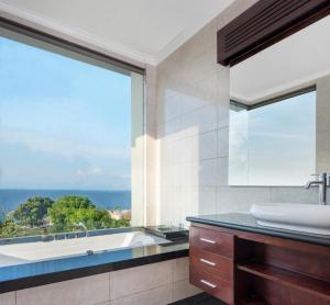 a bathroom with a tub and a sink and a window at Blue Point Resort and Spa in Uluwatu