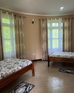 1 Schlafzimmer mit 2 Betten und 2 Fenstern in der Unterkunft KARUSIRO FARM AND COUNTRY PARK in Kibaha