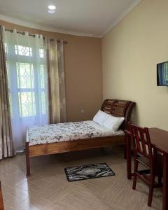 Schlafzimmer mit einem Bett, einem Tisch und einem Fenster in der Unterkunft KARUSIRO FARM AND COUNTRY PARK in Kibaha