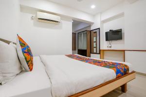 a bedroom with a bed and a tv on the wall at FabHotel RVG, Alkapuri Vadodara in Vadodara