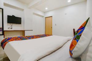 a white bed in a room with a television at FabHotel RVG, Alkapuri Vadodara in Vadodara