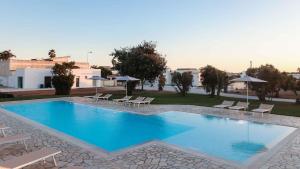 a large swimming pool with chairs and umbrellas at Tenuta Cursano in Santa Cesarea Terme