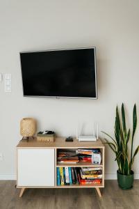 a tv on a white wall in a living room at Apartament ACTIV jezioro góry in Żywiec